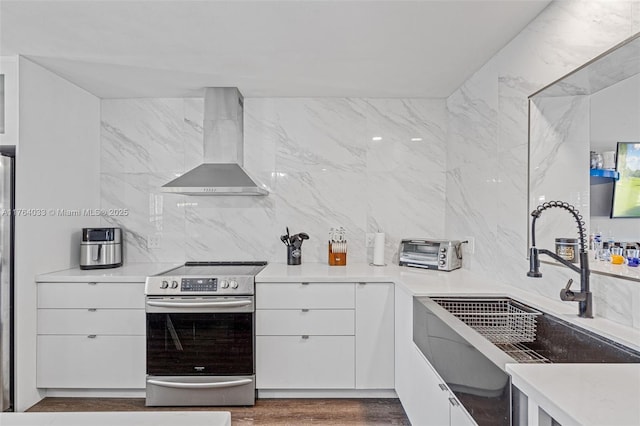 kitchen with electric range, modern cabinets, a sink, white cabinetry, and wall chimney range hood