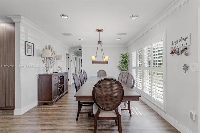 dining room with wood finished floors, visible vents, baseboards, ornamental molding, and a notable chandelier