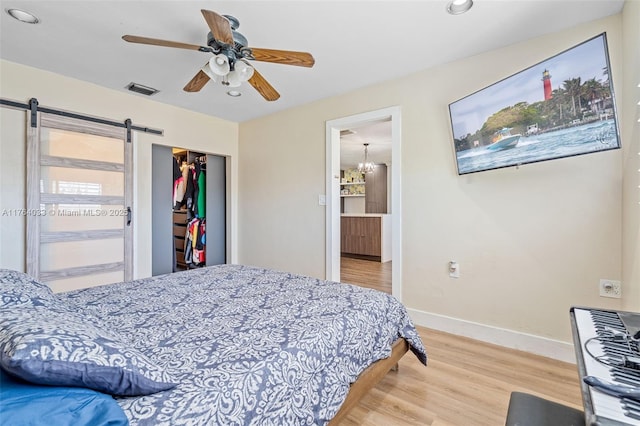 bedroom with visible vents, wood finished floors, a closet, a barn door, and baseboards