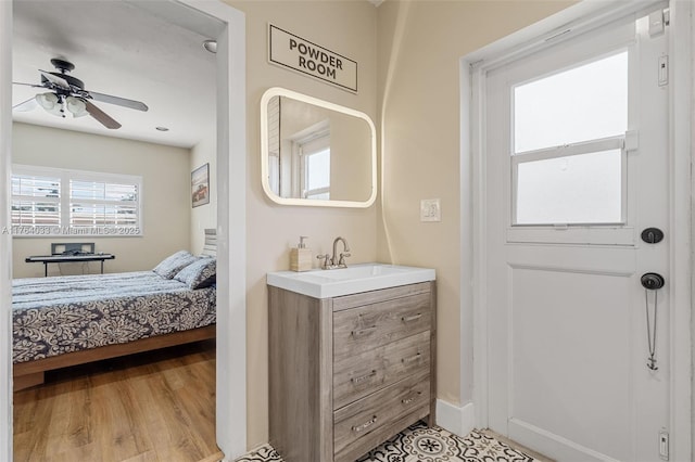 ensuite bathroom with vanity, wood finished floors, baseboards, ensuite bath, and ceiling fan