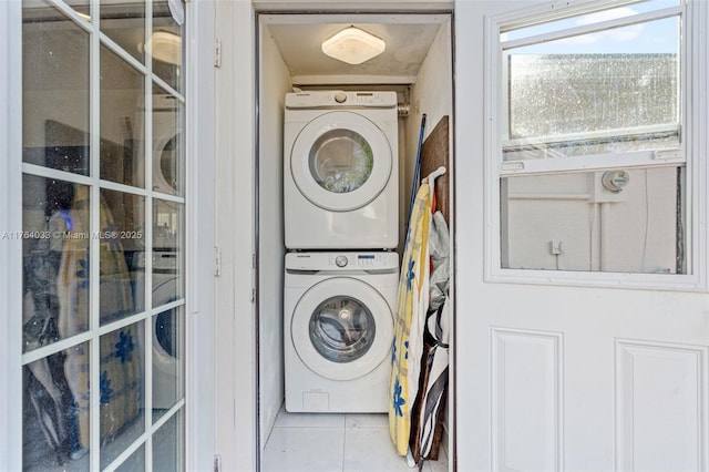 laundry area featuring tile patterned flooring, laundry area, and stacked washing maching and dryer