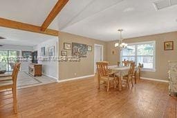 dining room with an inviting chandelier, beam ceiling, wood finished floors, and baseboards