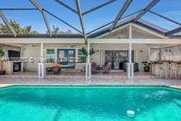 outdoor pool featuring glass enclosure and a patio area