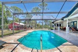 outdoor pool featuring glass enclosure and a patio area