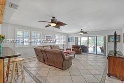 living area with light tile patterned floors and ceiling fan