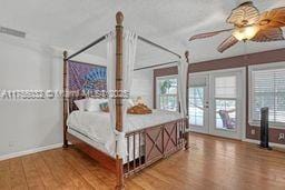 bedroom featuring wood finished floors, access to outside, multiple windows, and french doors