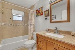 bathroom featuring toilet, vanity, and shower / bathtub combination with curtain