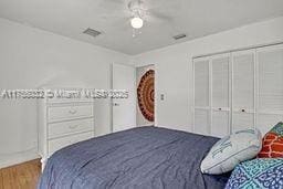 bedroom with ceiling fan, visible vents, a closet, and wood finished floors