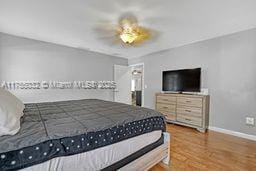 bedroom with a ceiling fan, baseboards, and wood finished floors