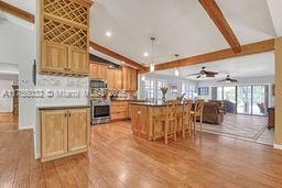 kitchen with beam ceiling, wood finished floors, wall oven, and ceiling fan