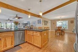 kitchen with dark countertops, decorative light fixtures, light wood-type flooring, beam ceiling, and stainless steel dishwasher