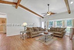 living room featuring plenty of natural light, vaulted ceiling with beams, a ceiling fan, and wood finished floors