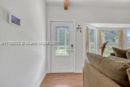 doorway featuring baseboards and beam ceiling