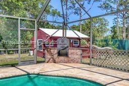 pool with a lanai, fence, and a patio