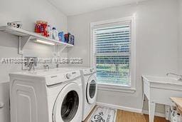 laundry room featuring baseboards, light wood-style floors, laundry area, and washing machine and clothes dryer