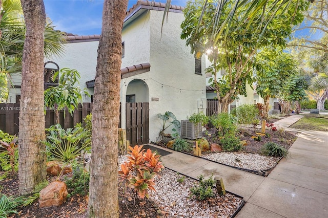 mediterranean / spanish home with a tiled roof, fence, and stucco siding