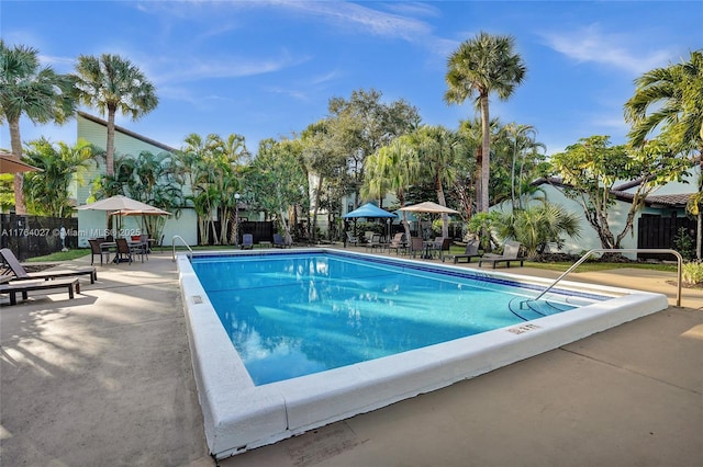 community pool with a patio and fence