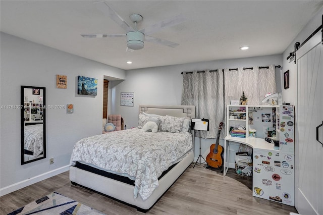 bedroom with a ceiling fan, wood finished floors, baseboards, recessed lighting, and a barn door