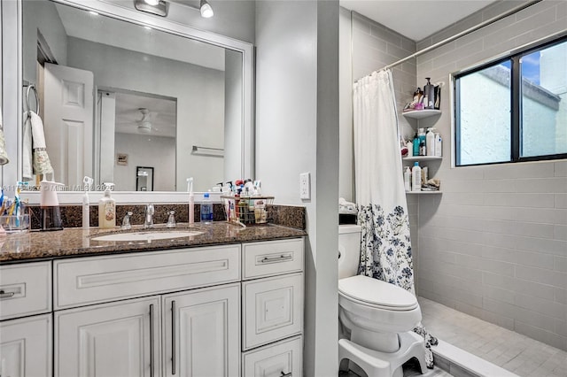 full bath featuring tiled shower, toilet, ceiling fan, and vanity