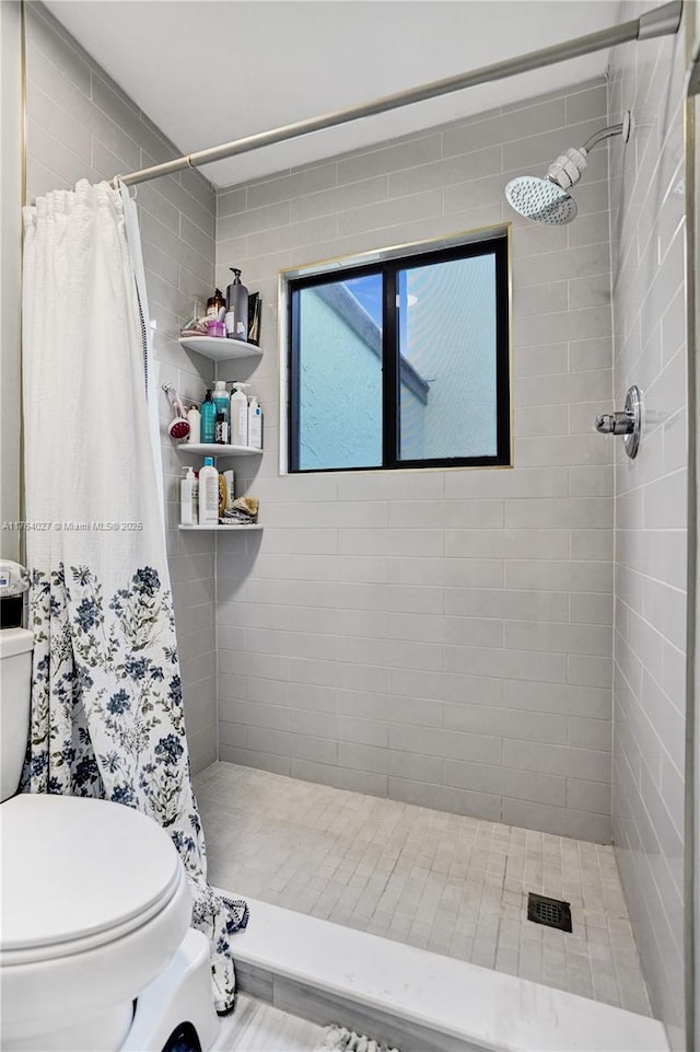 bathroom featuring tiled shower and toilet