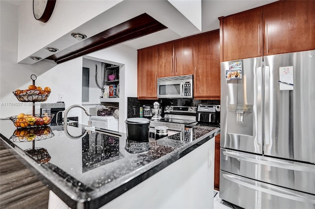 kitchen with tasteful backsplash, stainless steel appliances, brown cabinetry, and dark stone counters