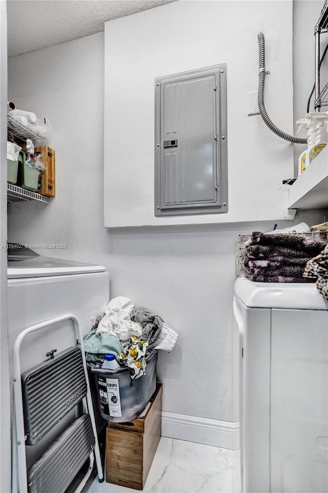 clothes washing area with baseboards, electric panel, laundry area, washer and dryer, and marble finish floor