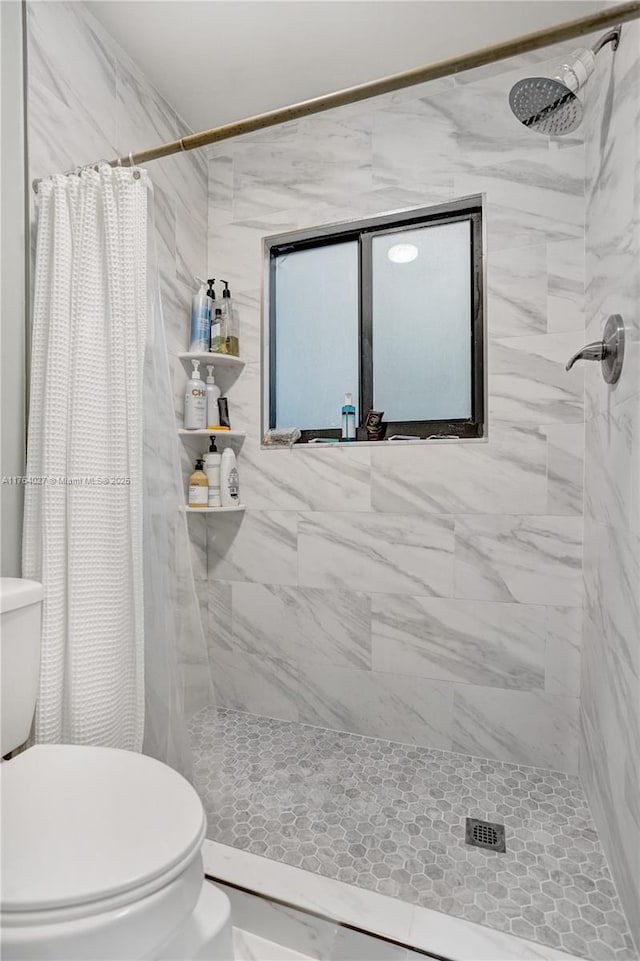 bathroom with tiled shower and toilet