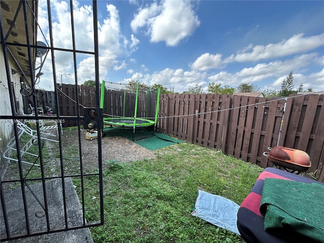 view of yard featuring a trampoline and a fenced backyard