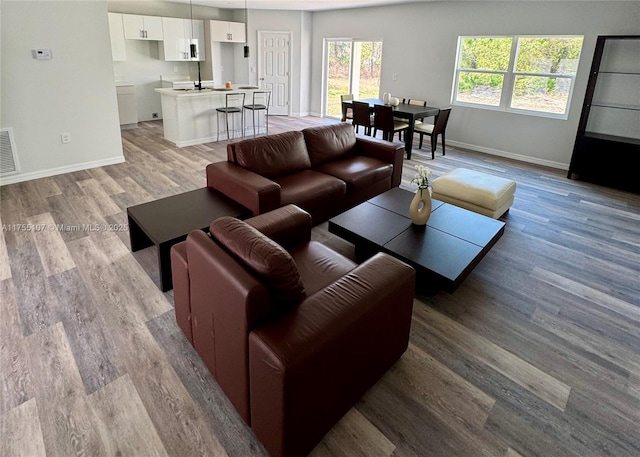 living room featuring visible vents, light wood-style flooring, and baseboards