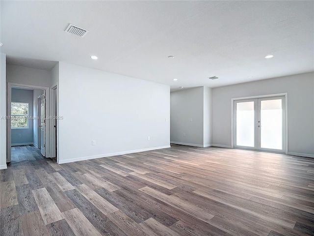 empty room featuring visible vents, baseboards, wood finished floors, and french doors