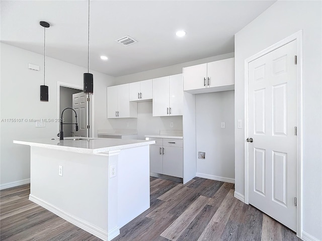 kitchen with visible vents, an island with sink, a sink, wood finished floors, and white cabinets