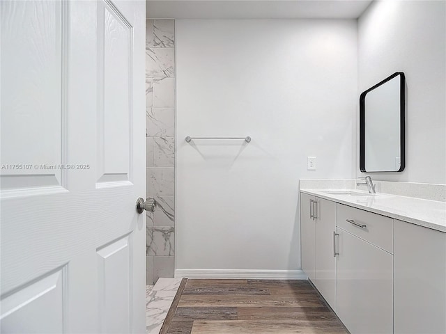 full bathroom featuring tiled shower, vanity, baseboards, and wood finished floors