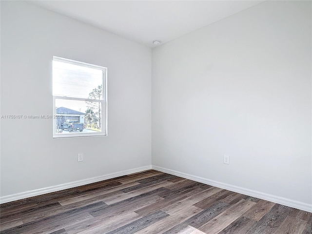 spare room featuring baseboards and wood finished floors