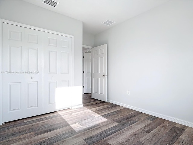 unfurnished bedroom with a closet, visible vents, and dark wood-style floors