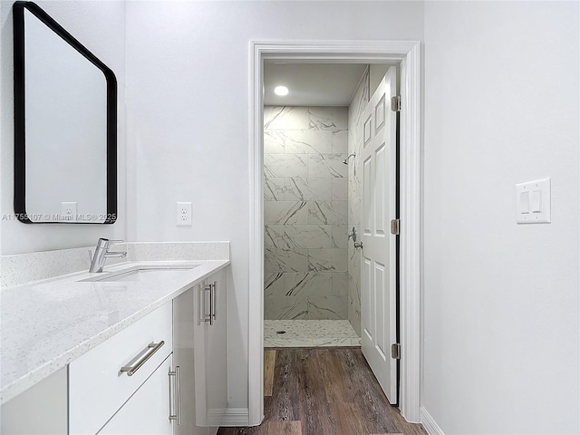 full bath featuring baseboards, vanity, wood finished floors, and a shower stall