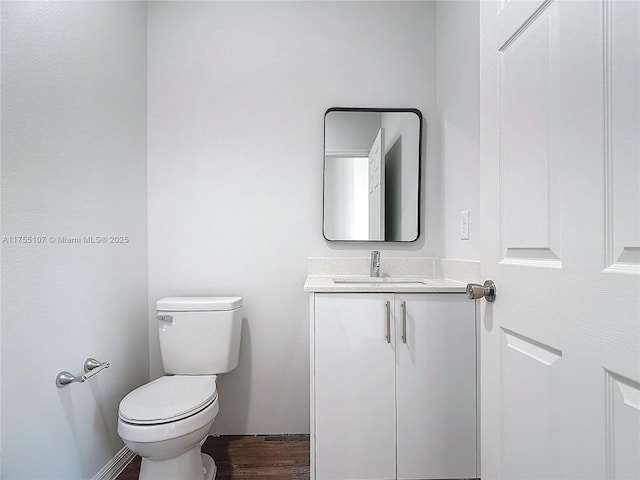 half bathroom featuring toilet, wood finished floors, and vanity