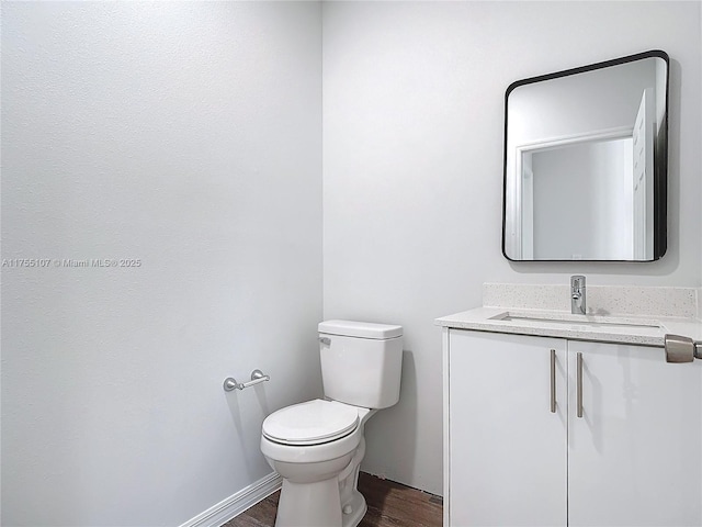 bathroom featuring vanity, toilet, wood finished floors, and baseboards