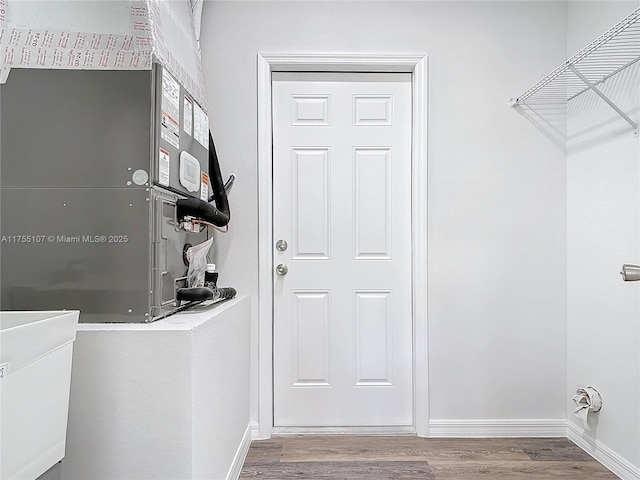 clothes washing area with baseboards and wood finished floors