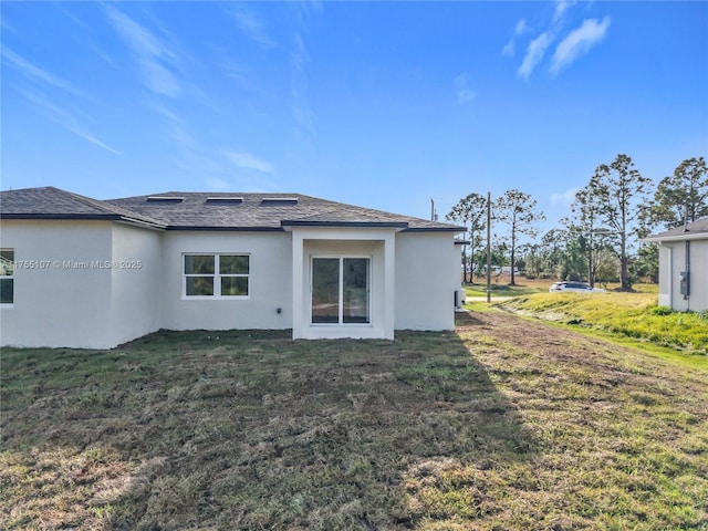 back of house featuring a lawn and stucco siding