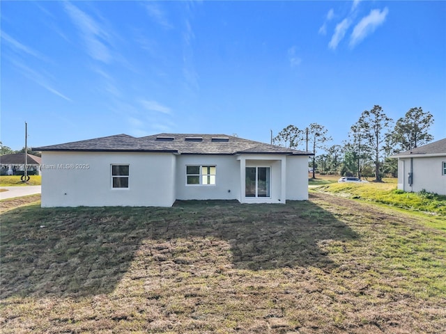 rear view of property featuring a yard and stucco siding