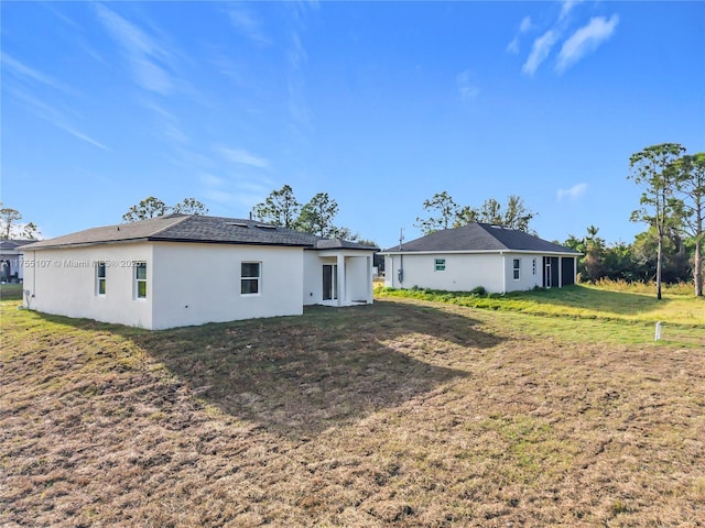 back of property featuring a yard and stucco siding