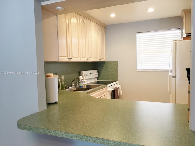 kitchen featuring white appliances, dark countertops, and recessed lighting