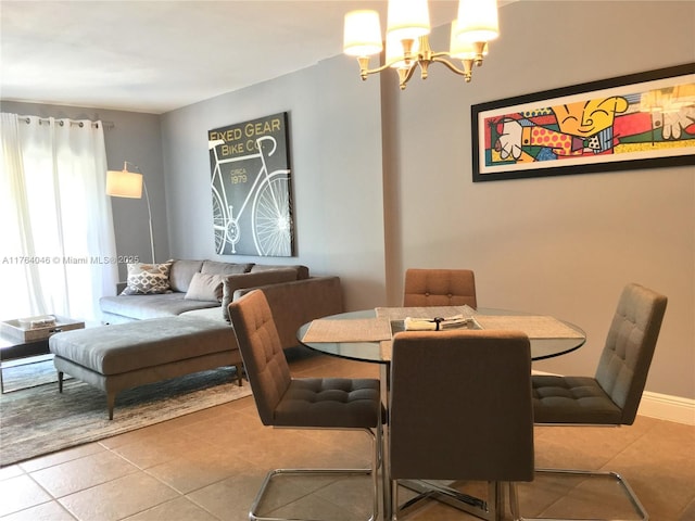 tiled dining space featuring an inviting chandelier and baseboards