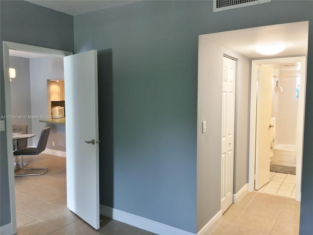 hallway with tile patterned floors, baseboards, and visible vents