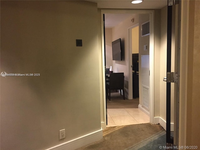 hallway with tile patterned floors, visible vents, carpet floors, and baseboards