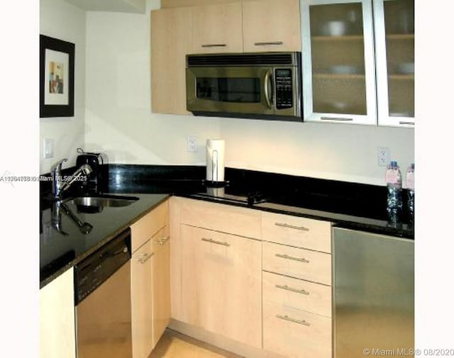 kitchen with stainless steel microwave, glass insert cabinets, light brown cabinets, and dishwashing machine