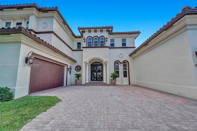 view of front facade featuring a tiled roof, decorative driveway, and stucco siding