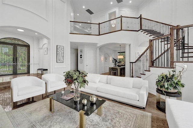 living area featuring arched walkways, french doors, stairs, and a high ceiling