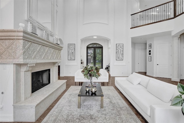 living room featuring baseboards, arched walkways, a towering ceiling, and a premium fireplace