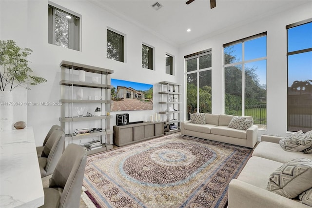 living area with visible vents, crown molding, ceiling fan, recessed lighting, and a high ceiling